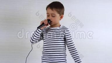 男孩拿着麦克风唱歌，他的脸表达情绪，面部表情，手势。 小可爱